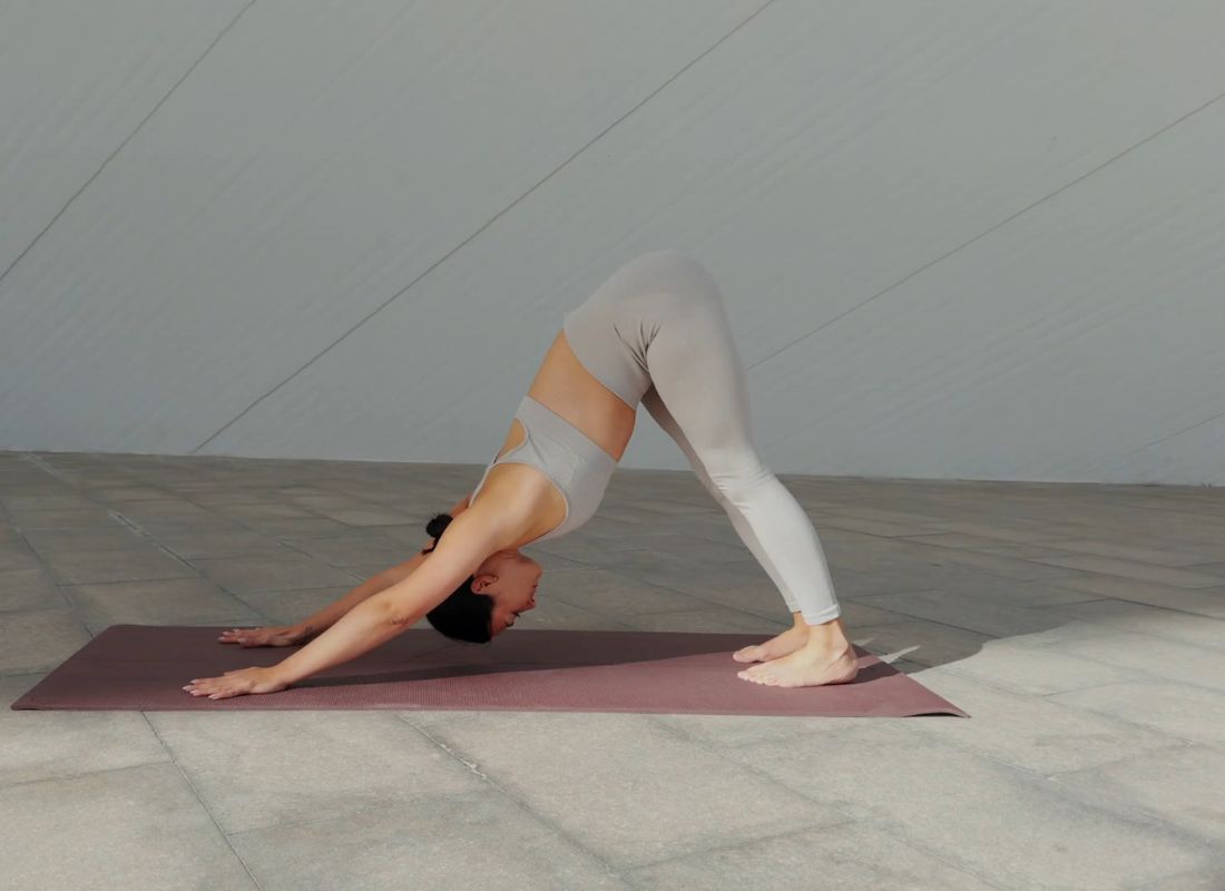 devojka izvodi joga vežbu Pas koji gleda dole