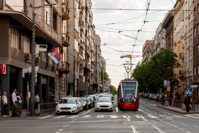 Gradska ulica u Srbiji sa tramvajem, automobilima i pešacima, prikaz urbane saobraćajne infrastrukture
