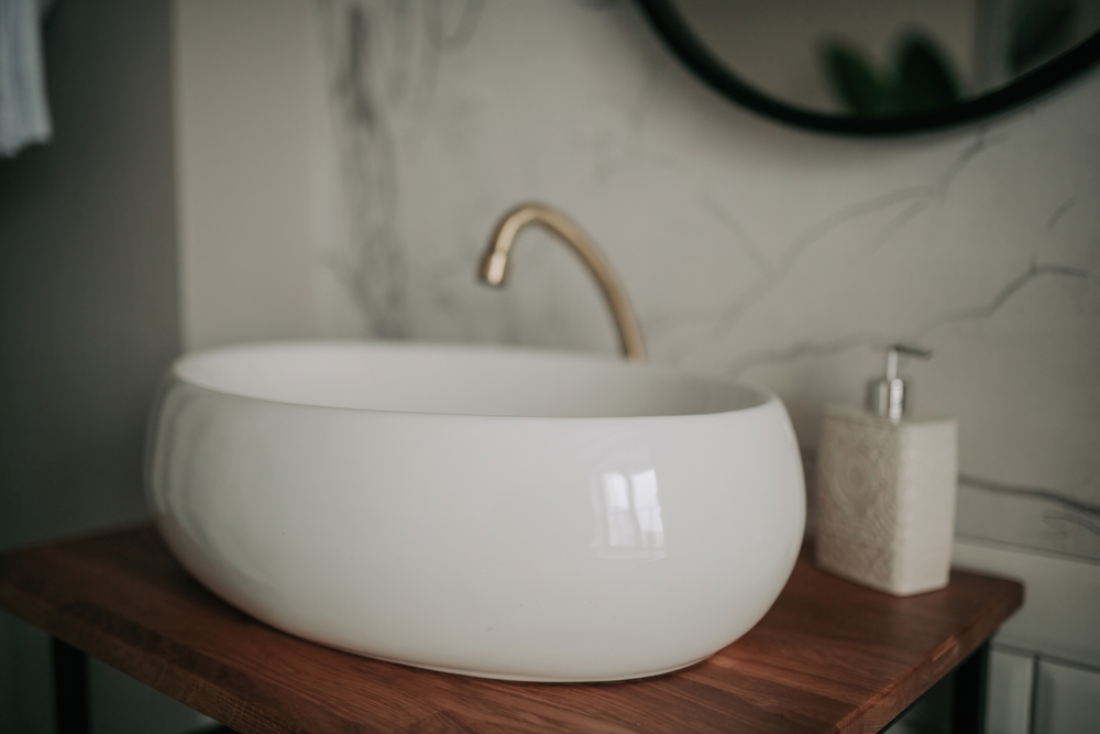 Moderan beli lavabo na drvenoj površini uz bež i prirodne tonove u kupatilu