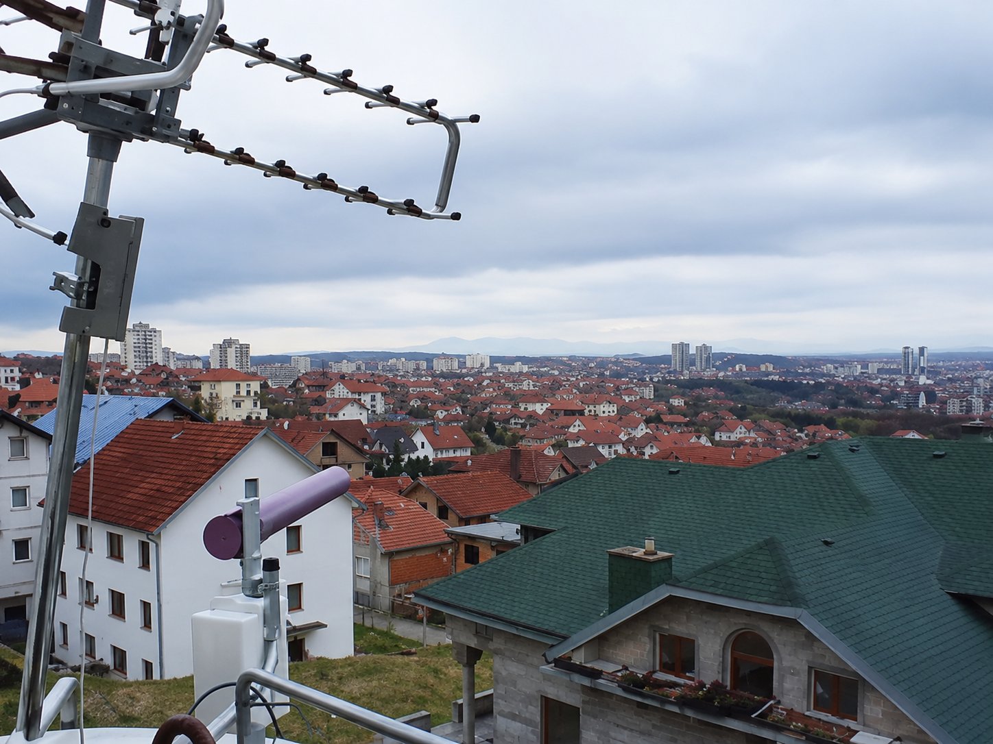 Panoramski pogled sa visoke terase preko beogradskih krovova, stambenih zgrada i udaljenih brda