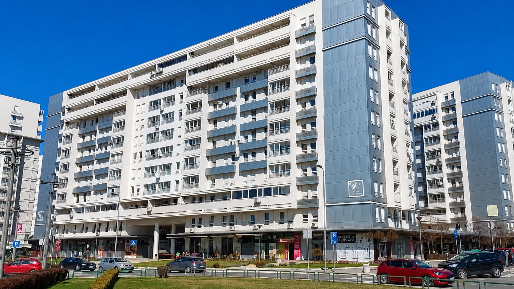 Moderne višespratne stambene zgrade sa terasama uz prometnu ulicu na Novom Beogradu.